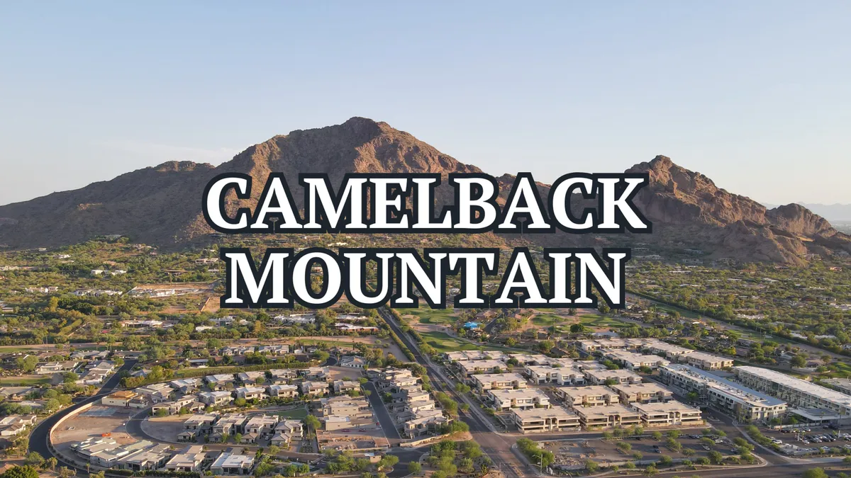 Camelback Mountain rises above a surrounding neighborhood and green park areas, offering a sense of scale and adventure. The image conveys the allure of hiking and iconic desert views, with clear visibility of the renowned trails and open community spaces.