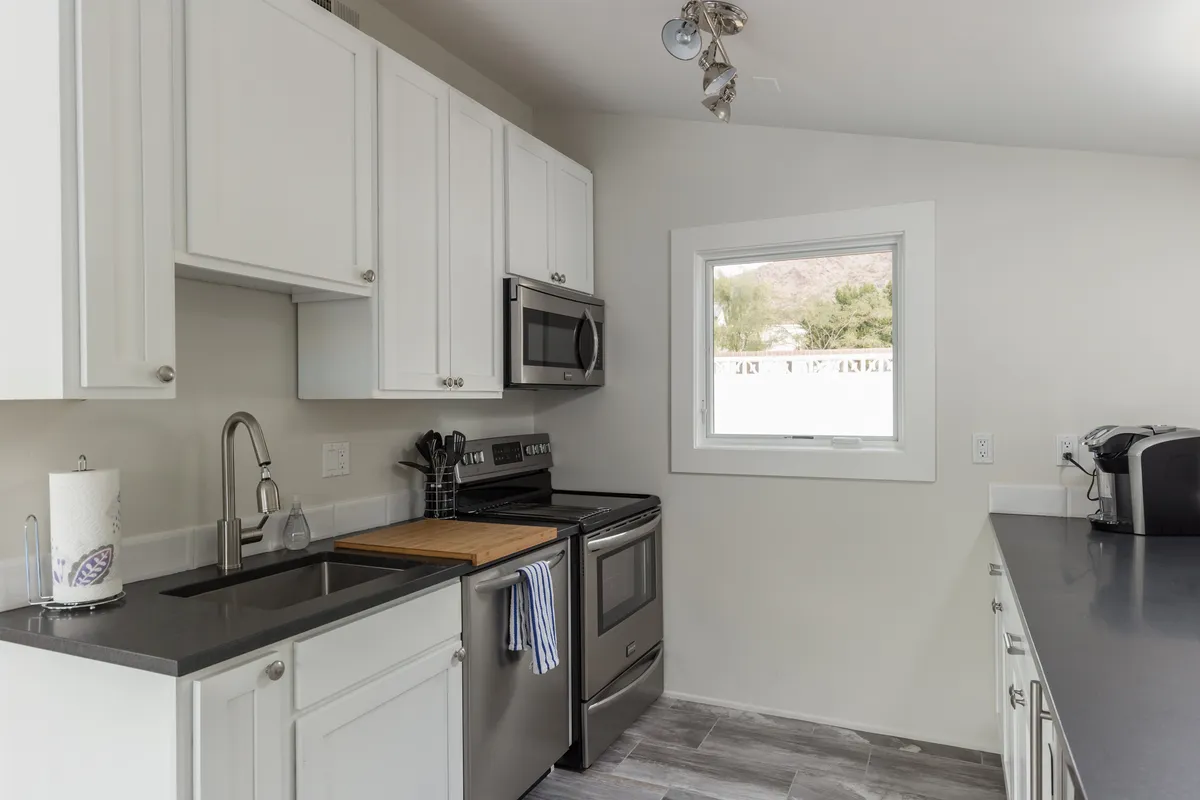 A closer view of a kitchen area with stainless steel appliances, granite countertops, and a window offering a scenic view. The scene conveys a cozy yet modern mood, ideal for both morning routines and preparing family recipes.